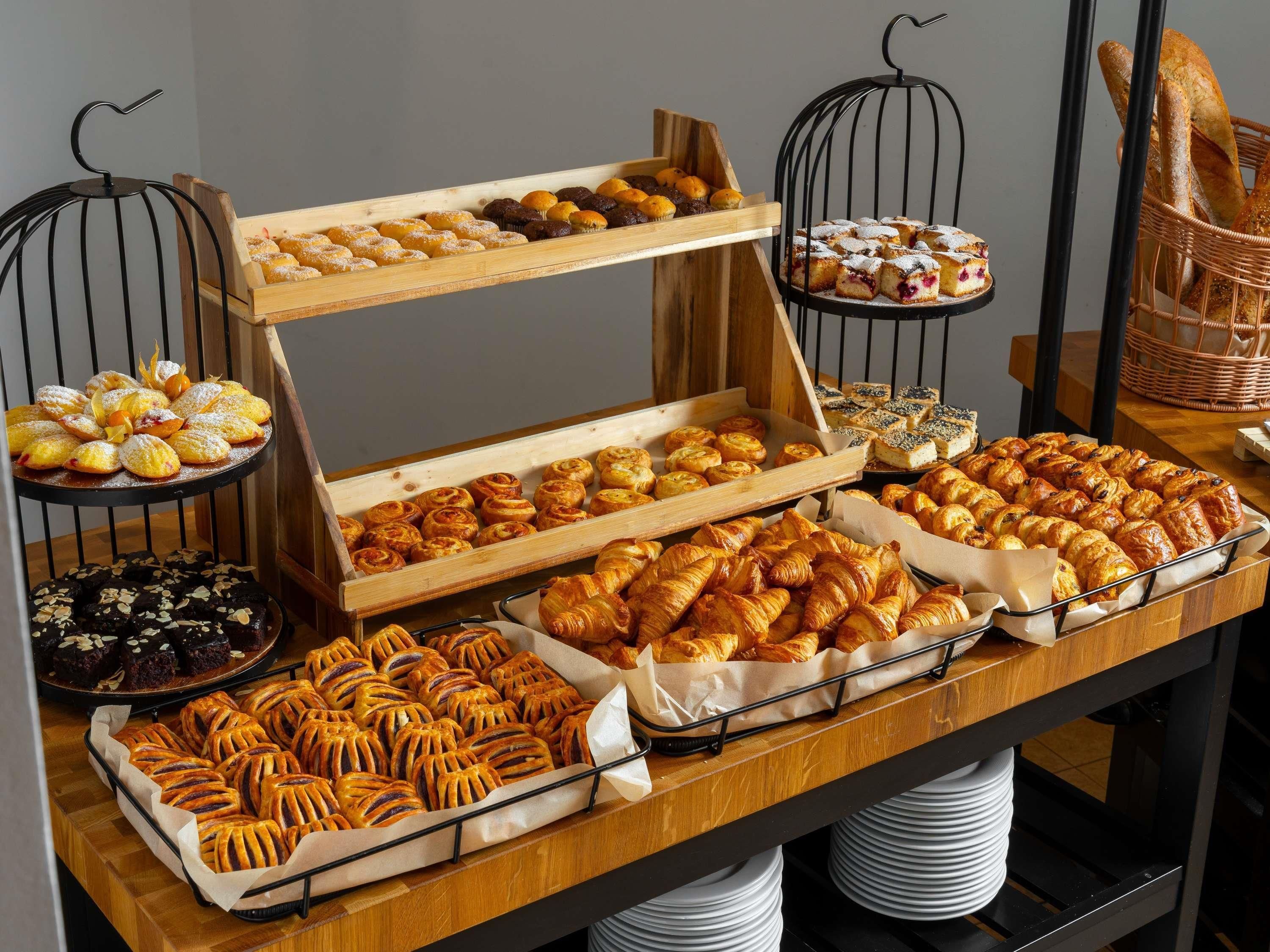 A buffet table with various baked goods, including pastries and bread, arranged on wooden boards and trays.