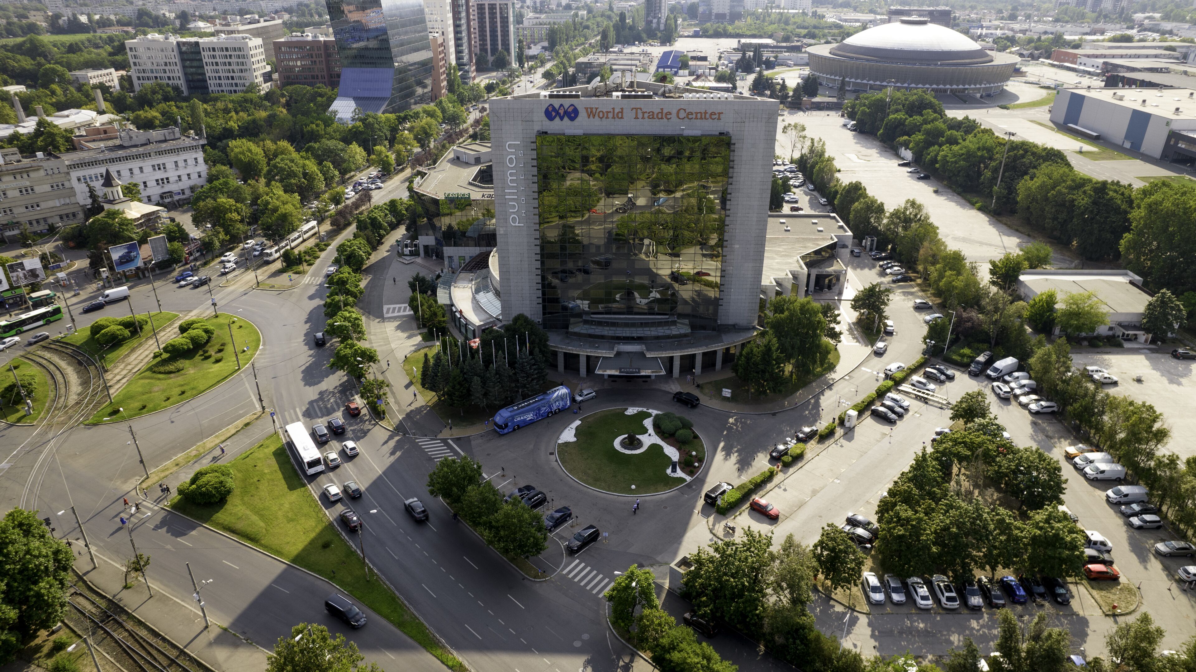 A large building with a prominent archway labeled "World Trade Center" and a circular plaza with a fountain.