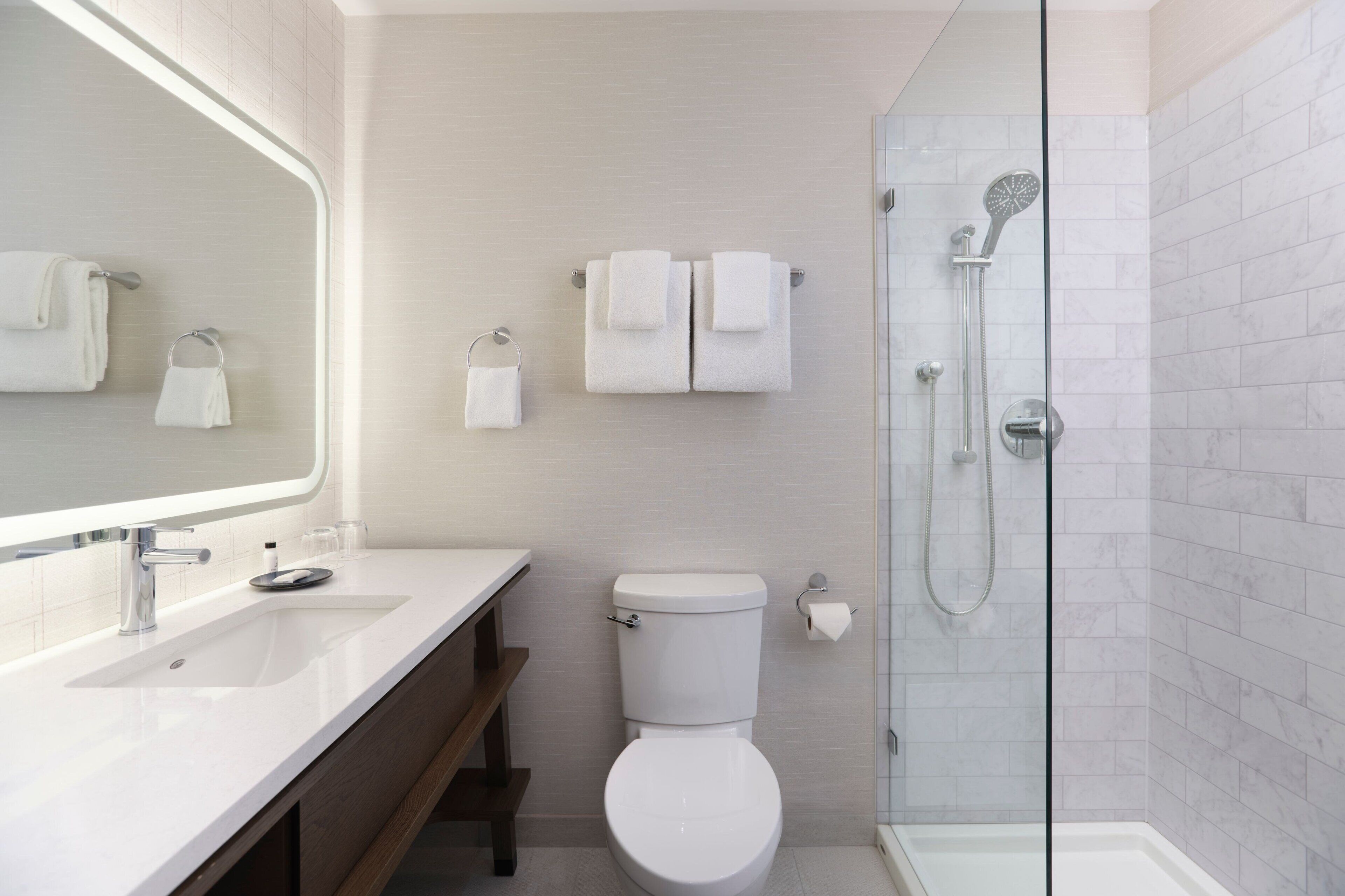 Ein modernes Badezimmer mit weißem Waschbecken, Toilette und einer Duschkabine aus Glas.