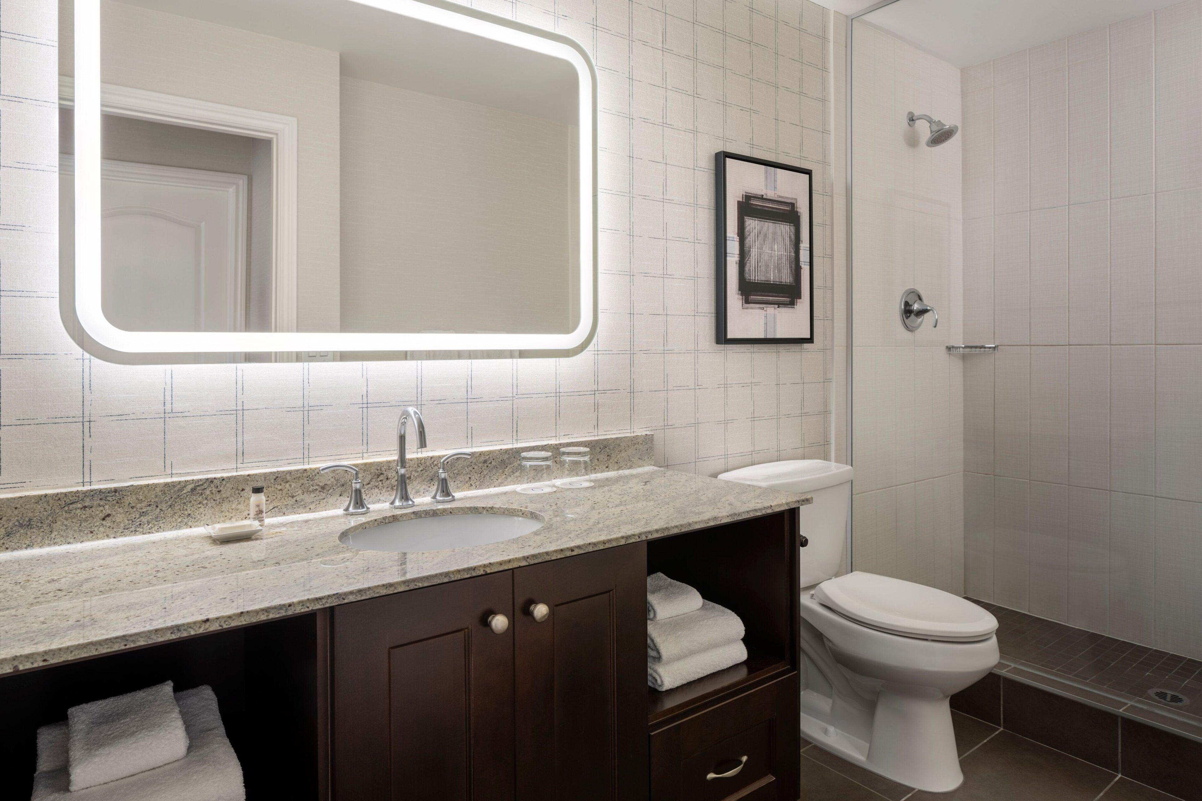 A modern bathroom with a large mirror, sink, and toilet.