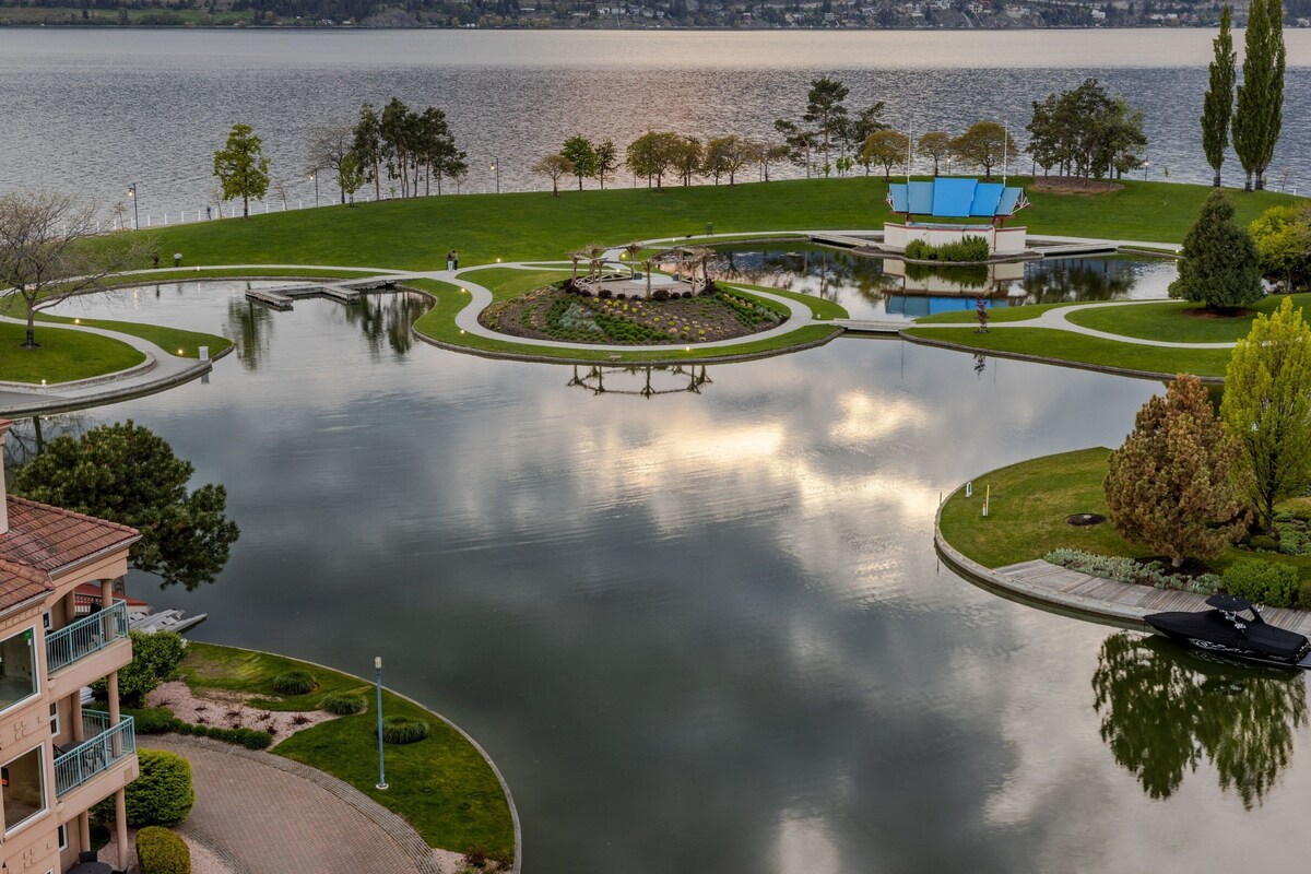 A lakeside park with a circular water feature, a gazebo, and a boat dock.