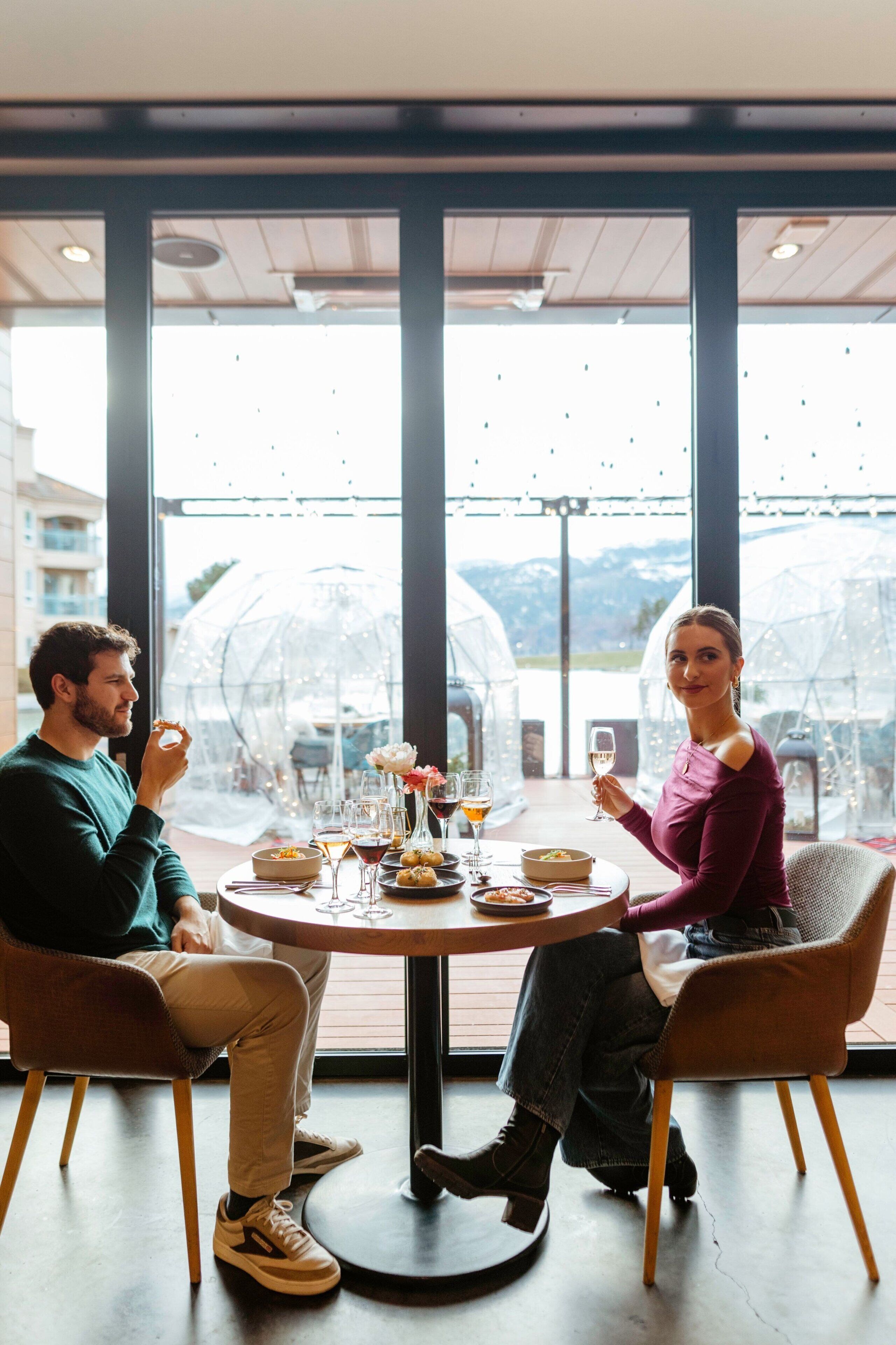 A couple dining at a round table with a view of the outdoors.