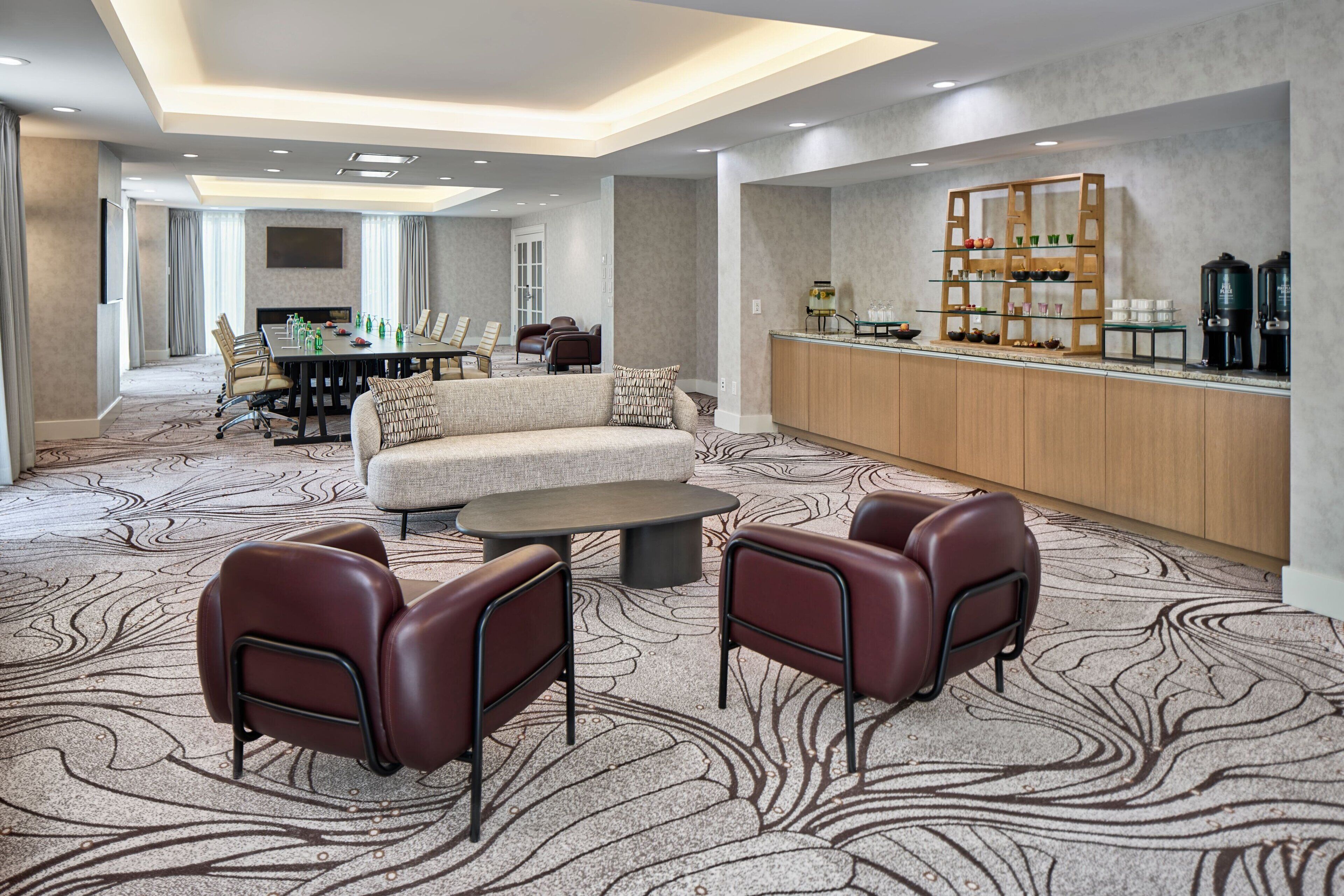 A modern hotel lobby with a seating area, a bar, and a conference room.