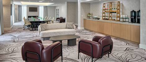 A modern hotel lobby with a seating area, a bar, and a conference room.