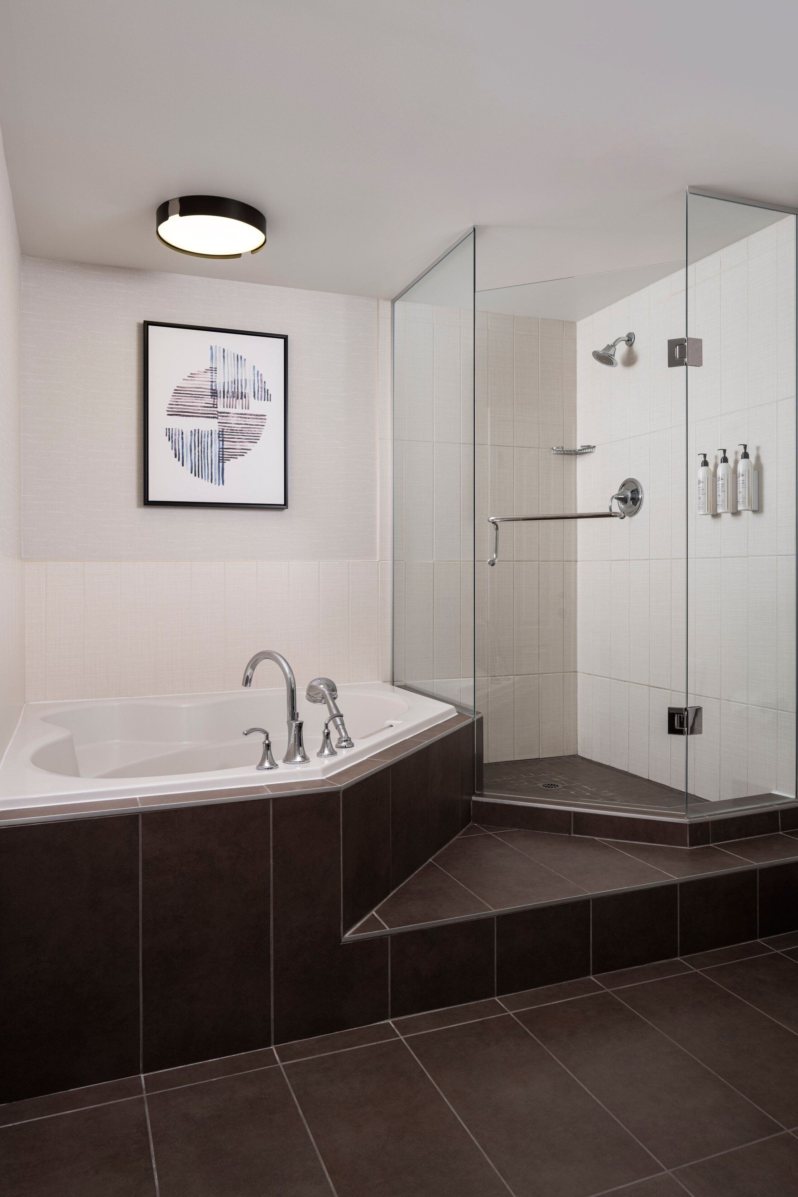 A modern bathroom with a freestanding bathtub, a glass-enclosed shower, and a framed artwork on the wall.