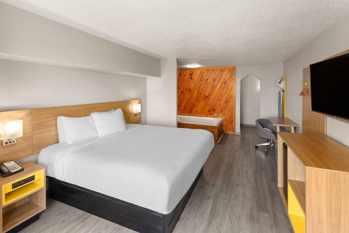 A modern hotel room with a large bed, bedside tables, a desk, and a television.
