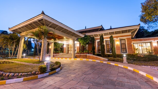 A building with a covered entrance, brick walls, and a well-lit garden area.