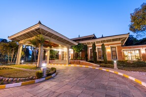 A building with a covered entrance, brick walls, and a well-lit garden area. - The Soaltee Kathmandu, Autograph Collection by Marriott (Kathmandu)