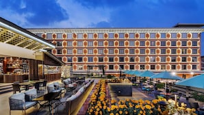 A hotel courtyard with outdoor seating, a flower bed, and a bar area.