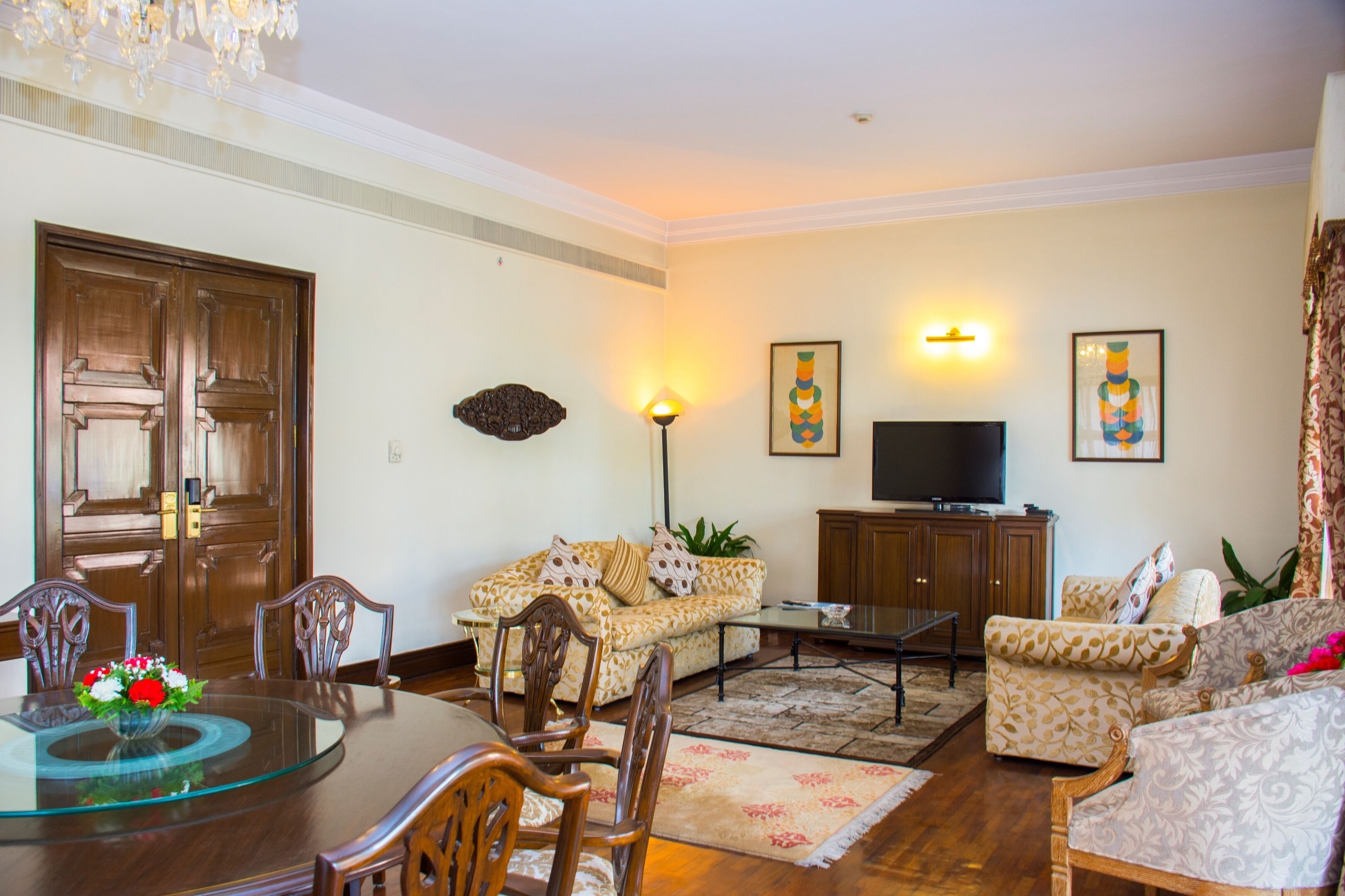 A living room with a dining table, sofas, a TV, and decorative items.