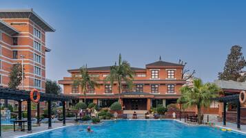 Relax by the tranquil pool surrounded by lush greenery and palm trees.