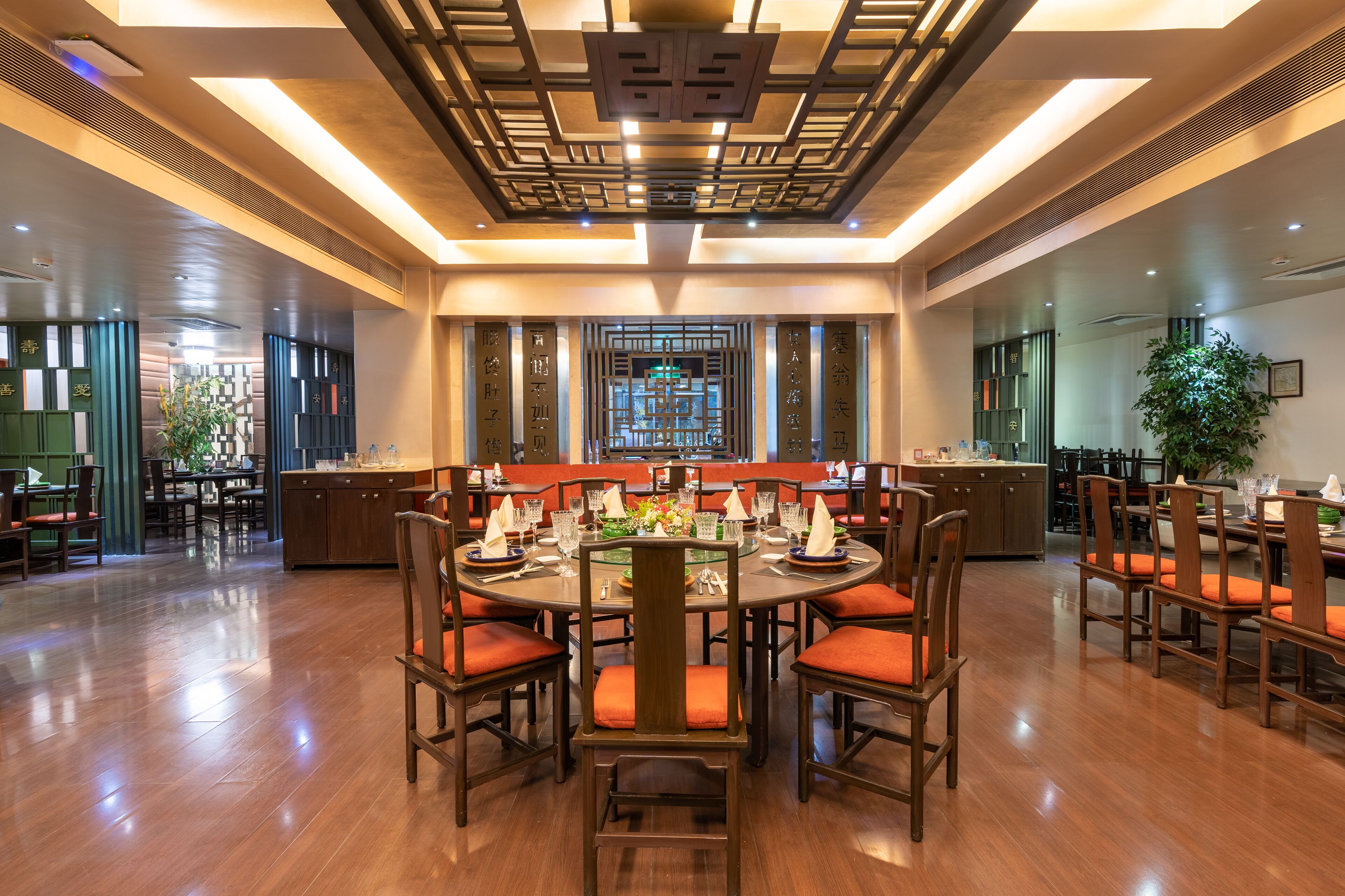 A spacious dining area with round tables, wooden chairs, and a central decorative element.