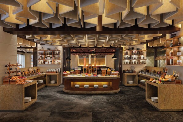 A breakfast buffet with a central serving area surrounded by shelves of condiments and jars.