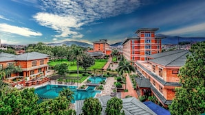 A resort with multiple buildings, a large swimming pool, and lush greenery.