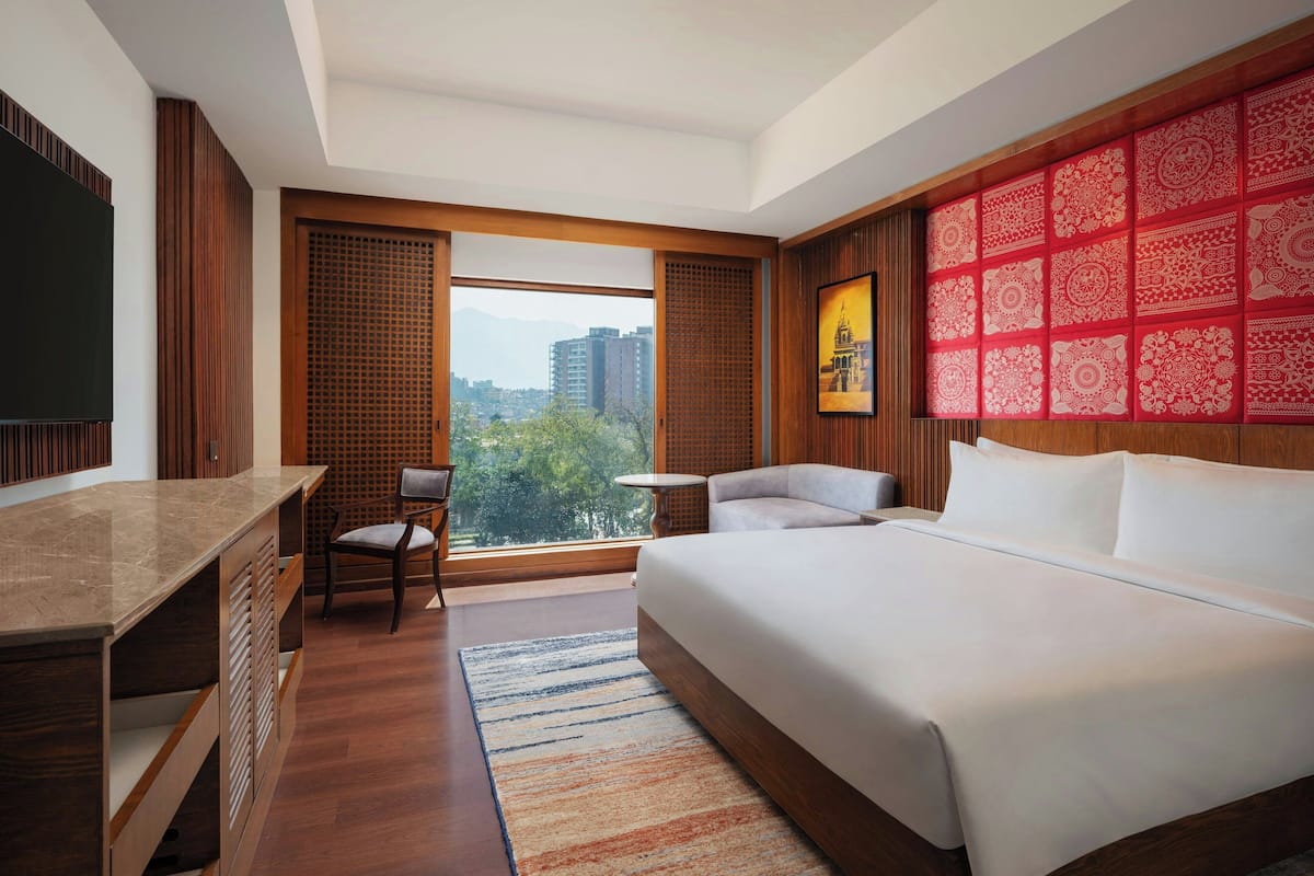 A hotel room with a large bed, a desk, a chair, and a view of the city.