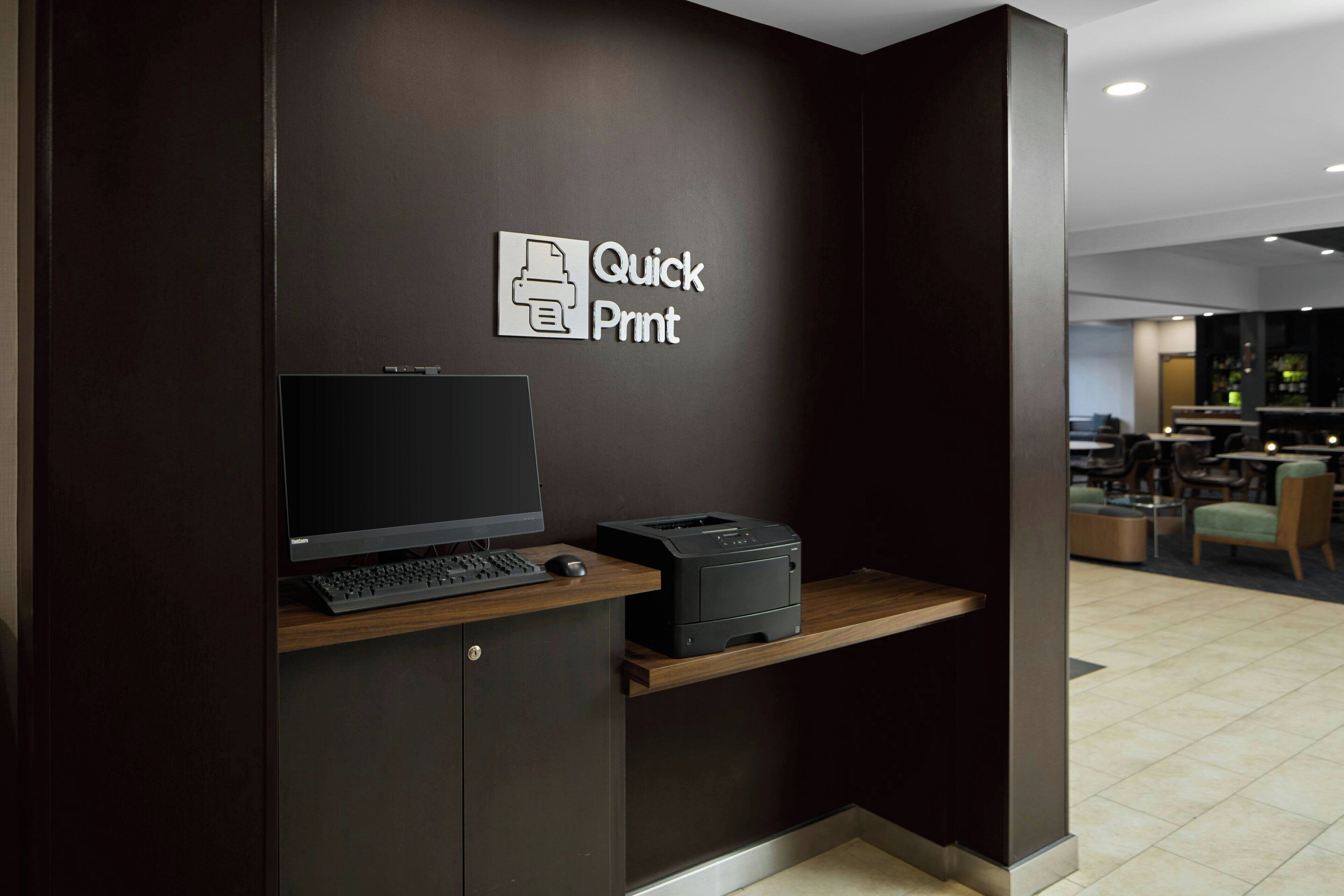 A reception desk with a computer, printer, and a sign that reads "Quick Print".