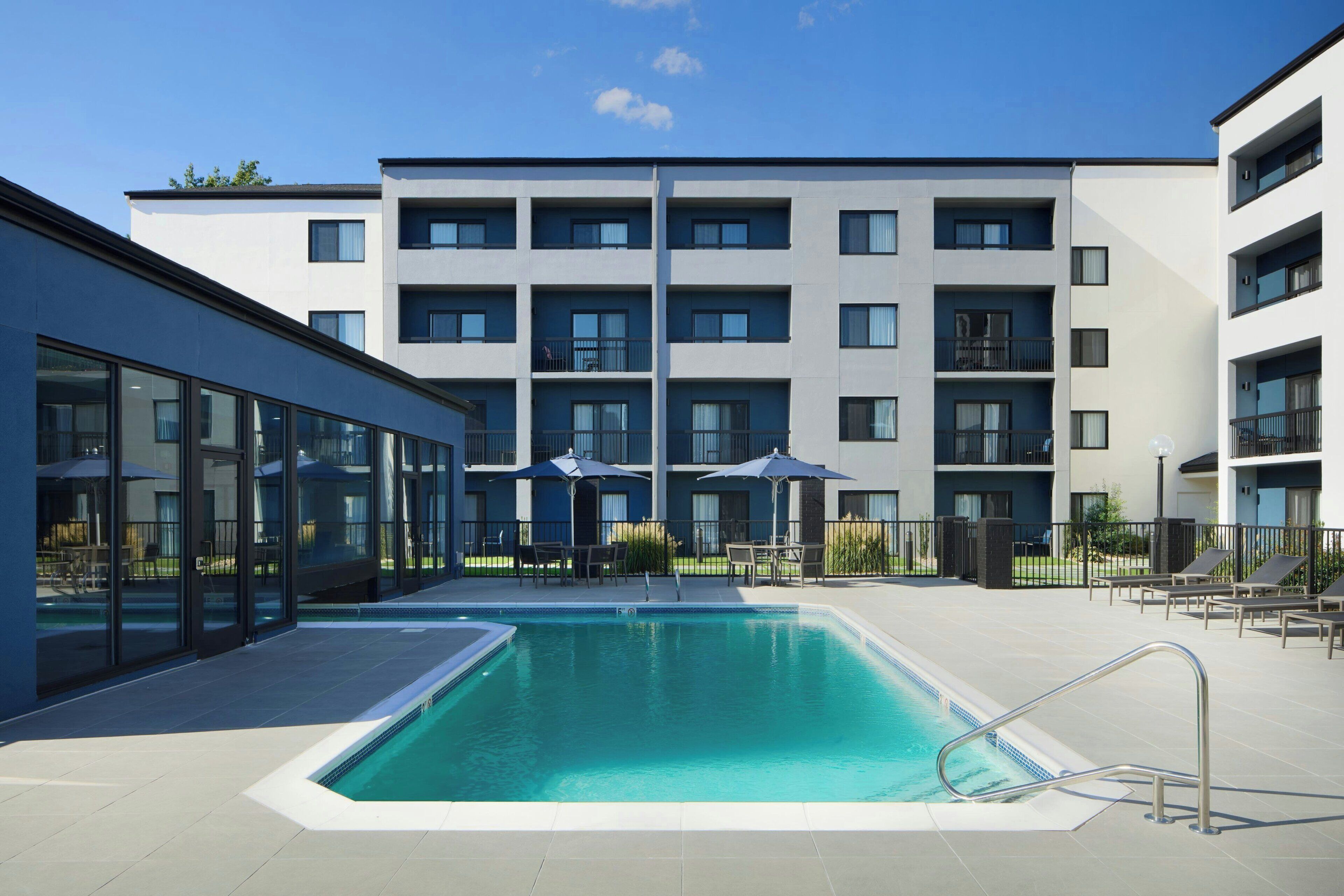 Un hôtel moderne doté d’une piscine, d’un espace extérieur aménagé et d’un immeuble à plusieurs étages avec des balcons.