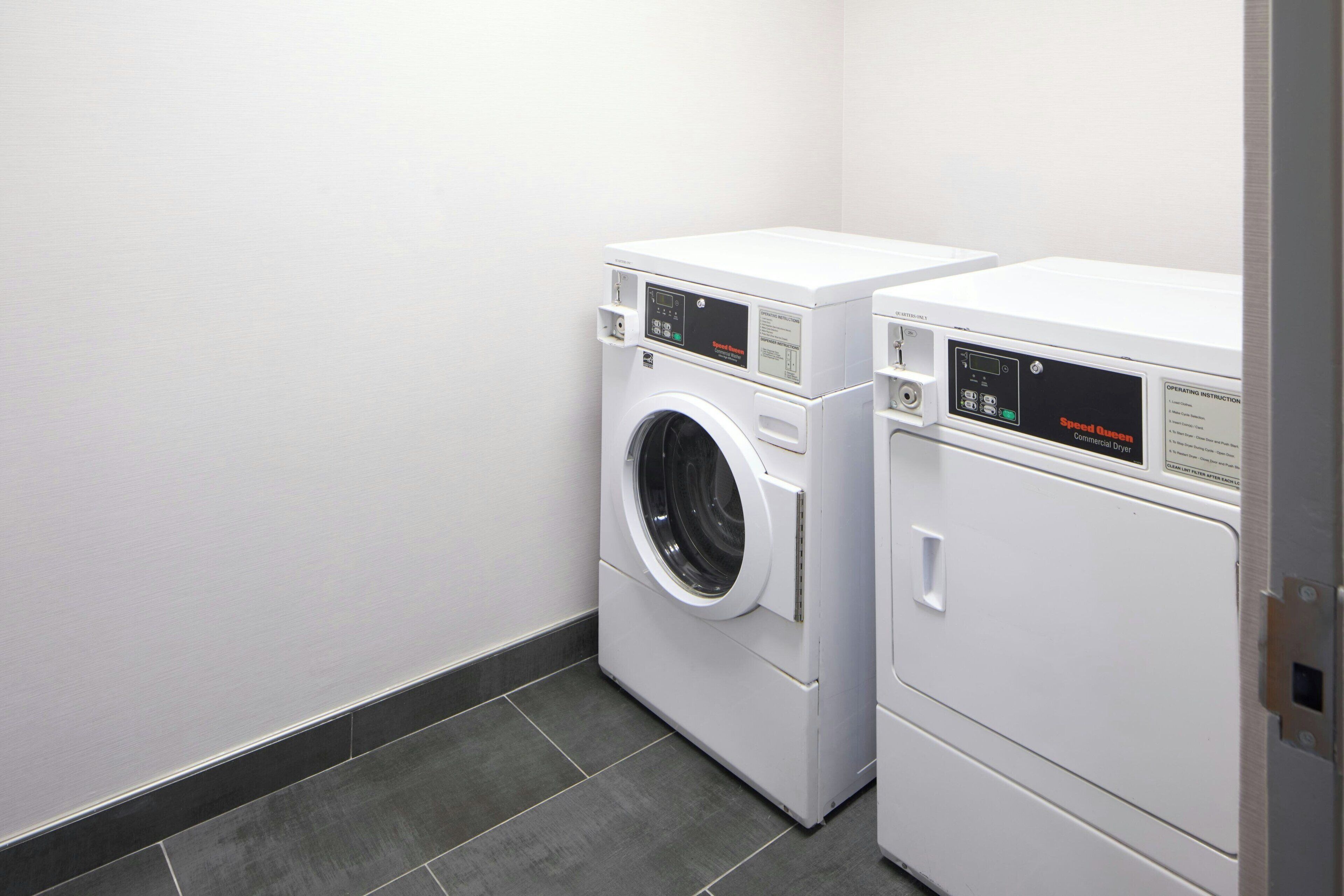 Une buanderie équipée de deux machines à laver à chargement frontal blanches et d’un sèche-linge.