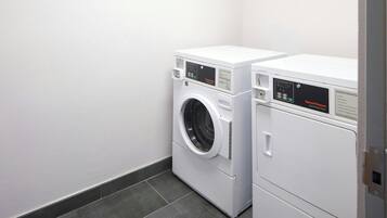 Une buanderie équipée de deux machines à laver à chargement frontal blanches et d’un sèche-linge.