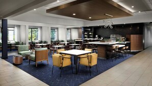 Un restaurante moderno con área de bar, diversas opciones de asientos, incluyendo mesas redondas y cabinas, y un gran ventanal que proporciona luz natural.