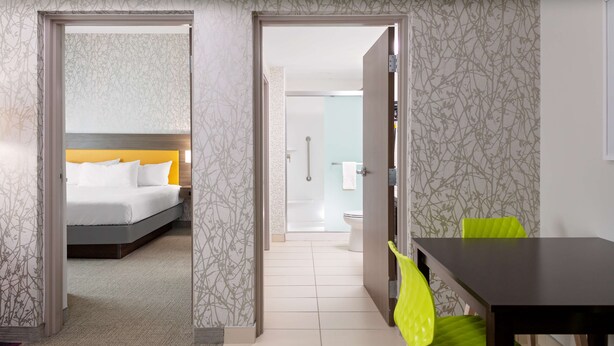 Habitación de hotel con cama, baño y zona de comedor con sillas.