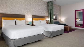 A hotel room with two beds, a mirror, a nightstand, and a green curtain.