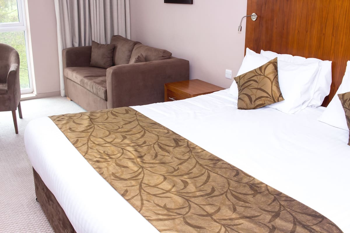 Une chambre d’hôtel avec un grand lit, un canapé et un fauteuil.