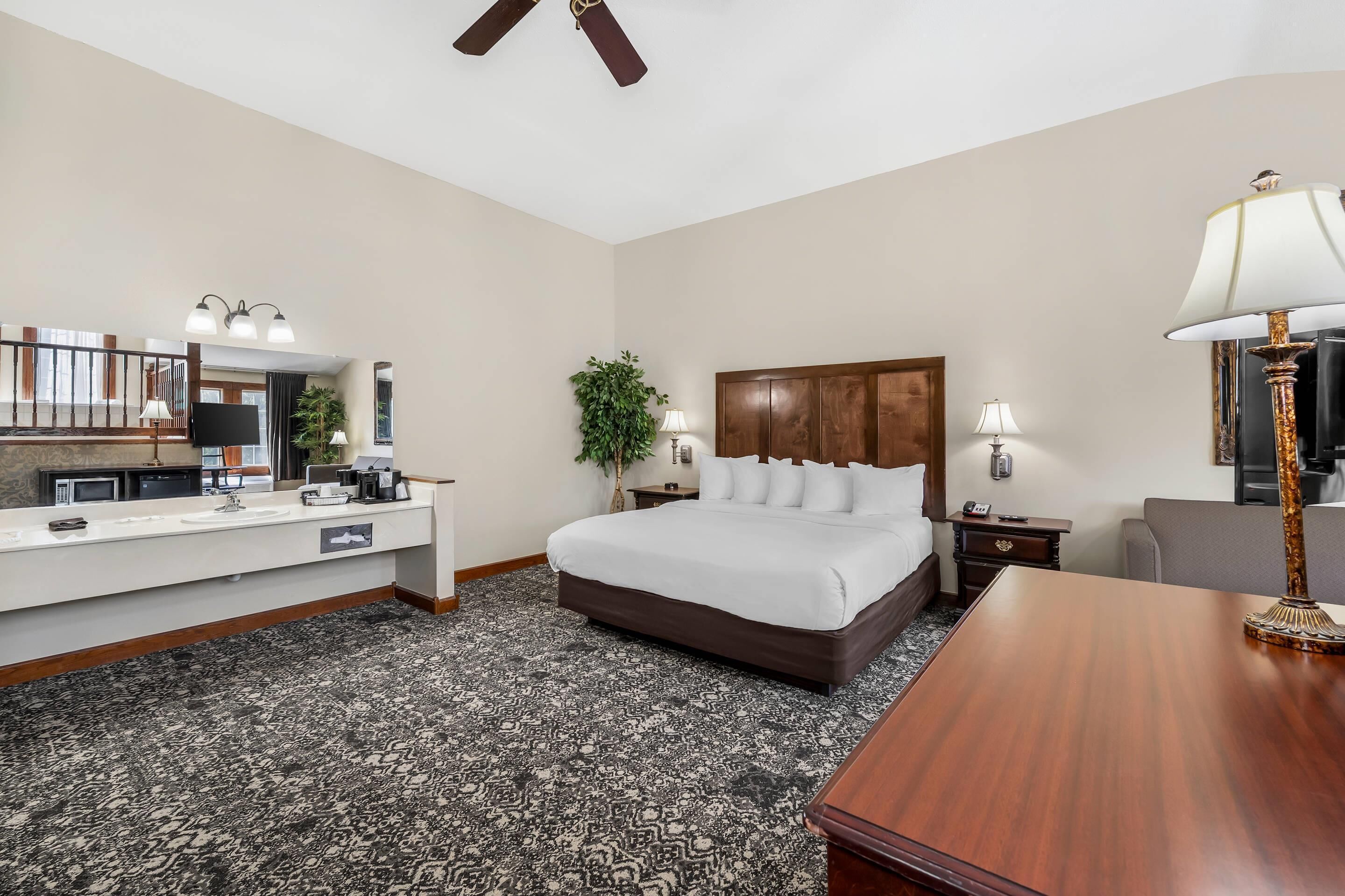 A hotel room with a bed, desk, and a large mirror.