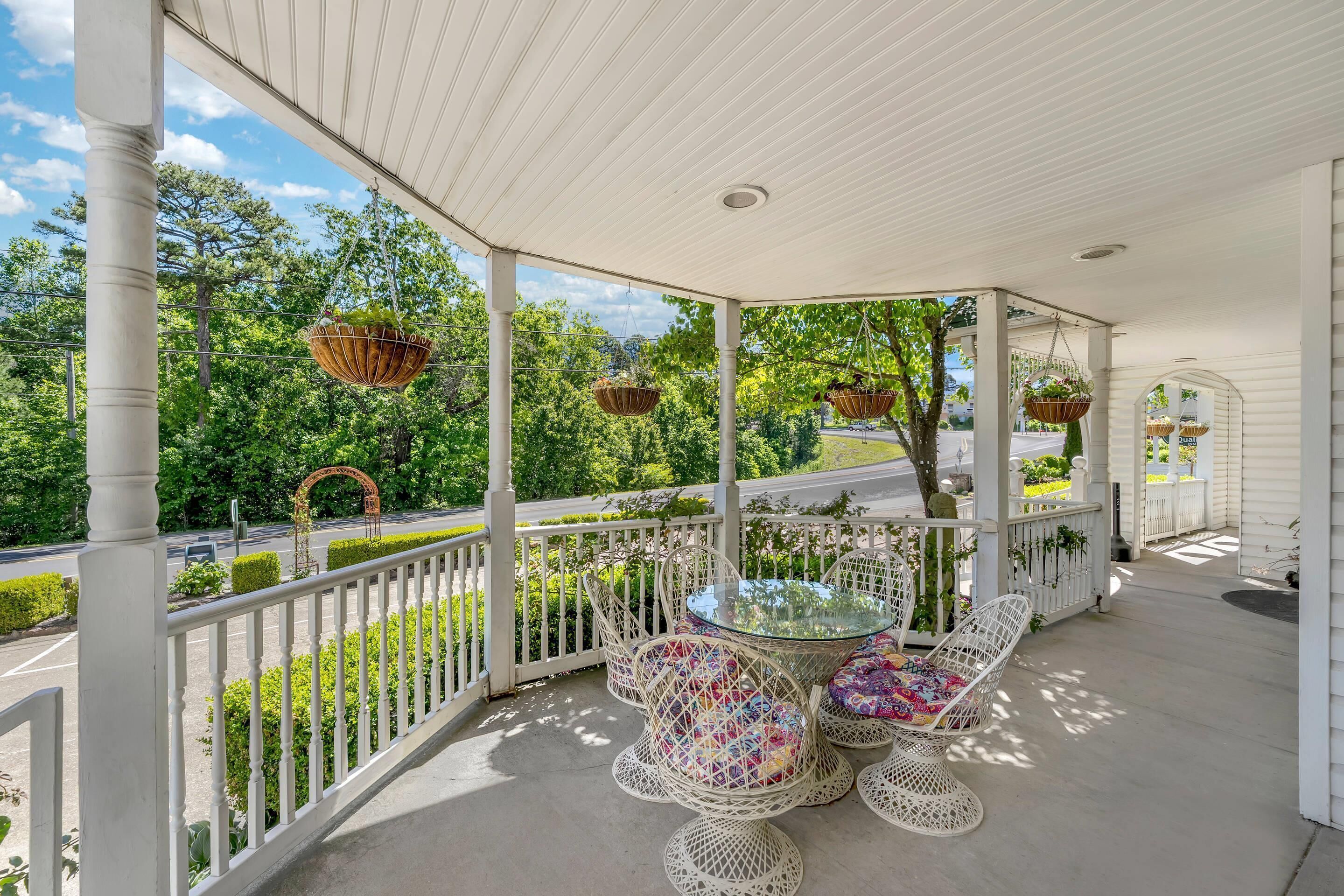 A covered porch with wicker furniture and hanging baskets.