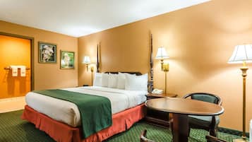Une chambre d’hôtel avec un lit, deux tables de chevet, une chaise et une petite table.