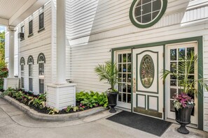A white building with a green door, a window with a decorative glass, and potted plants. - Quality Inn Eureka Springs South (Eureka Springs)