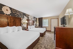 A hotel room with two beds, a TV, a desk, and a large floral wall mural. - Quality Inn Eureka Springs South (Eureka Springs)