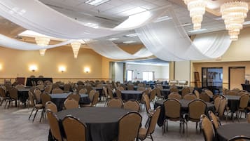 Une grande salle de conférence équipée de tables et de chaises, de lustres et de tentures décoratives au plafond.