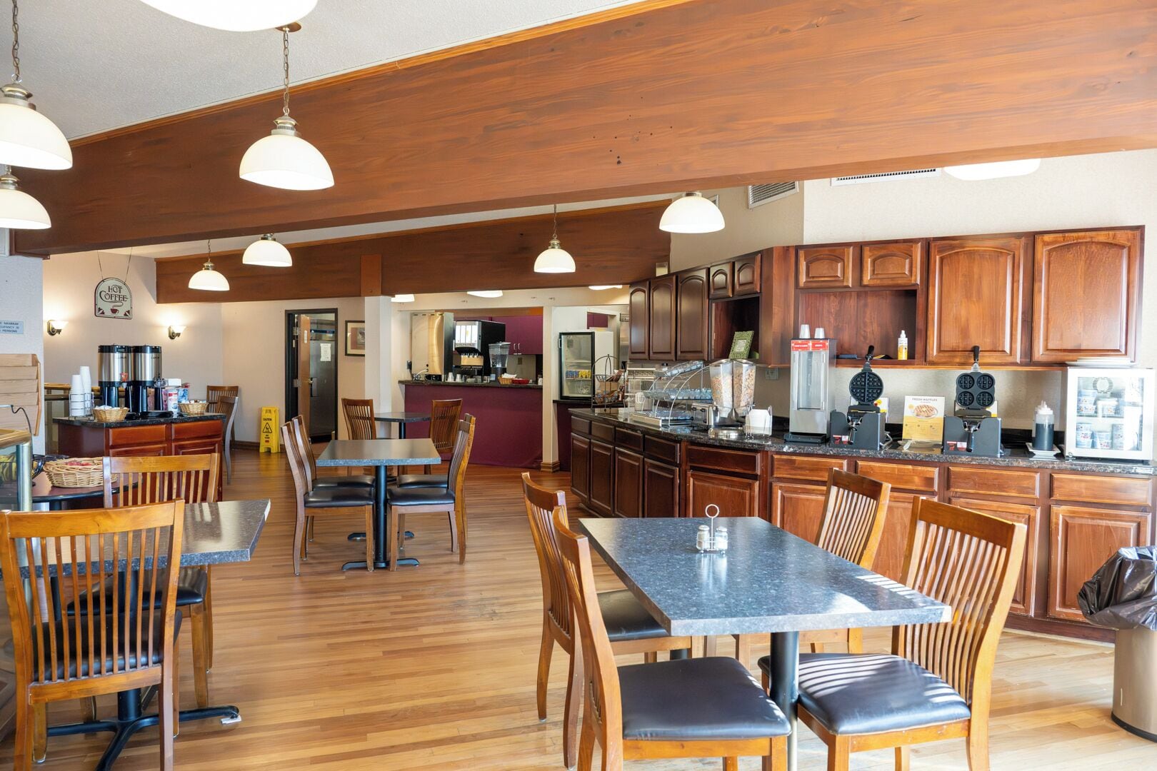 A spacious kitchen with wooden cabinets, a central island, and pendant lighting.