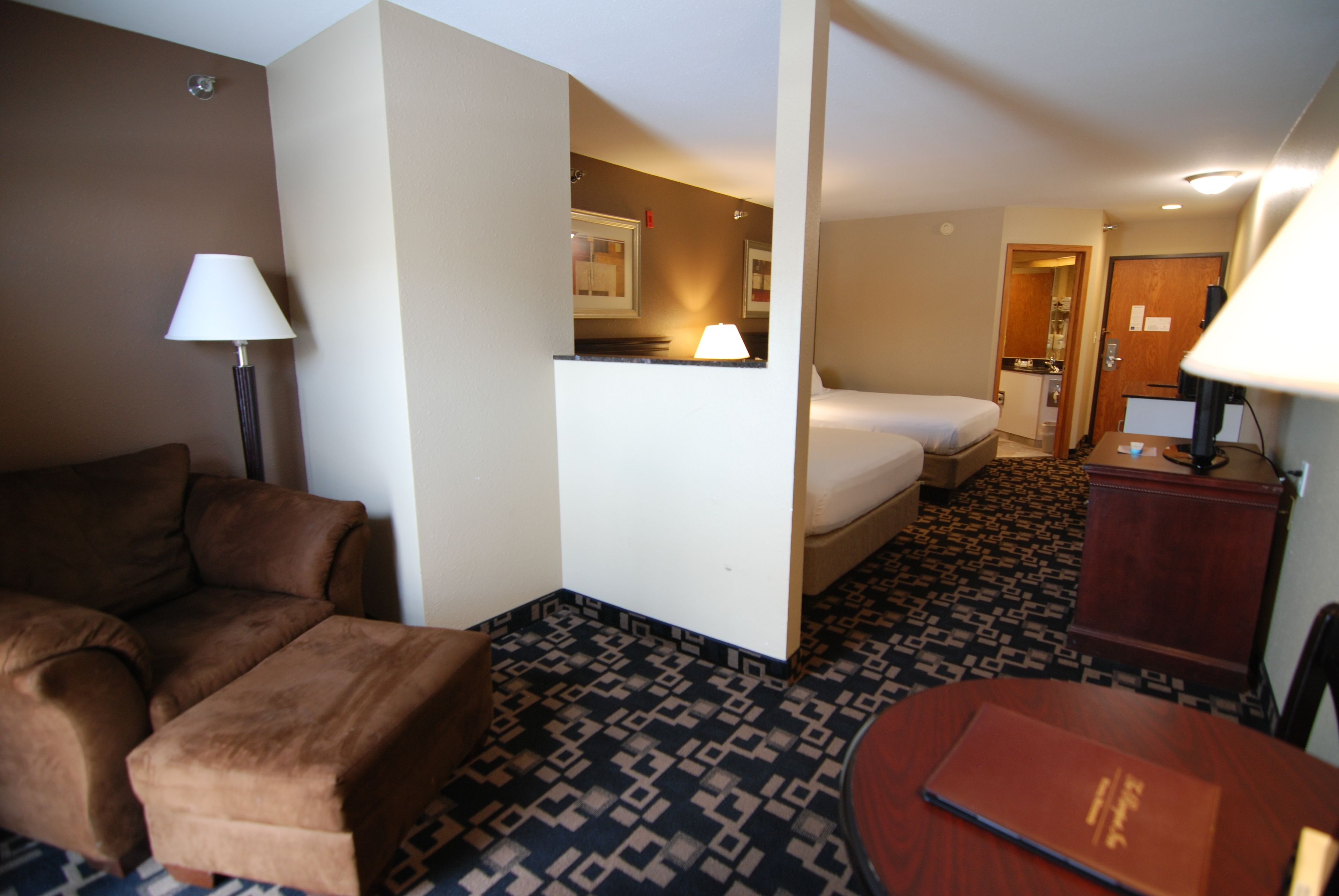 A hotel room with a sofa, a bed, a desk, and a lamp.