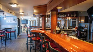 Un espace bar avec des tabourets de bar en bois, un comptoir et un panneau affichant le menu.
