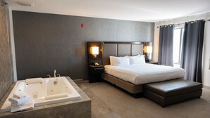 Une chambre d’hôtel avec un grand lit, une salle de bain séparée avec une baignoire et une petite table de chevet avec une lampe.
