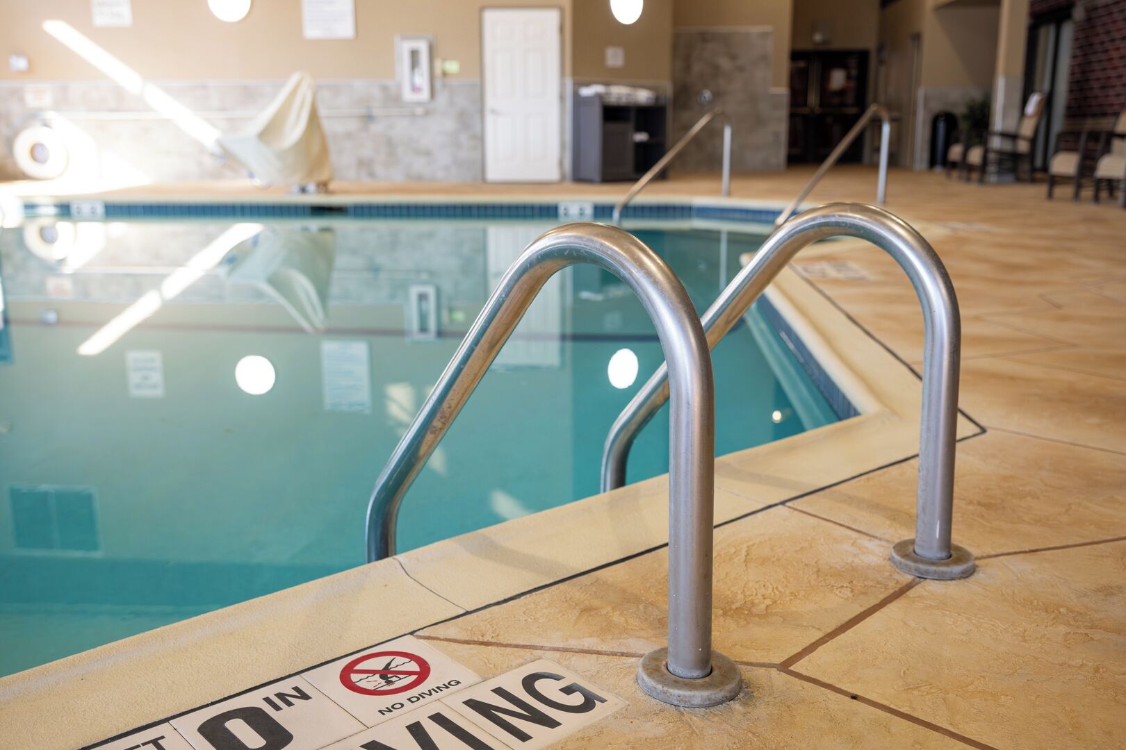 Zona de piscina con barandillas metálicas y un cartel que indica 'No Diving'.