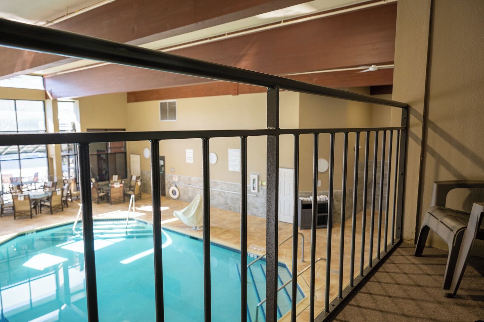 An indoor swimming pool with a view of the pool area, a seating area, and a door leading to another room.