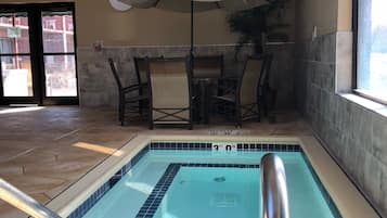 Piscina interior com profundidade de 90 centímetros, rodeada por paredes e piso revestidos em azulejo. Cadeiras e um guarda-sol estão próximos da piscina.