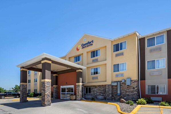 A Comfort Inn & Suites hotel with a covered entrance, stone pillars, and a parking lot.
