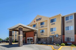 Un hotel Comfort Inn & Suites con entrada cubierta, pilares de piedra y estacionamiento.