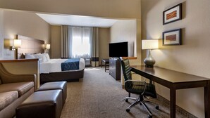 A hotel room with a bed, a desk, a chair, a TV, and a sofa. - Comfort Inn & Suites Waterloo - Cedar Falls (Waterloo)