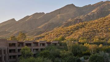 Paisaje desértico con montañas al fondo y un edificio de varios pisos en primer plano.