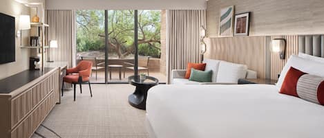 A hotel room with a large bed, a desk, a chair, a small table, and a view of the outdoors.
