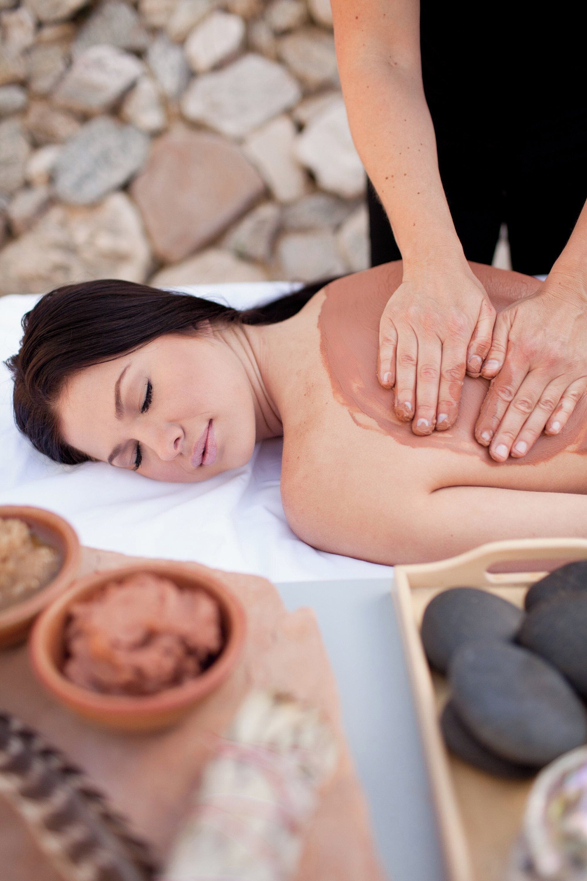 A massage therapy session with a person lying face down on a massage table, receiving a back massage.