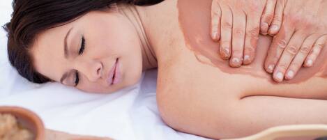 A massage therapy session with a person lying face down on a massage table, receiving a back massage.
