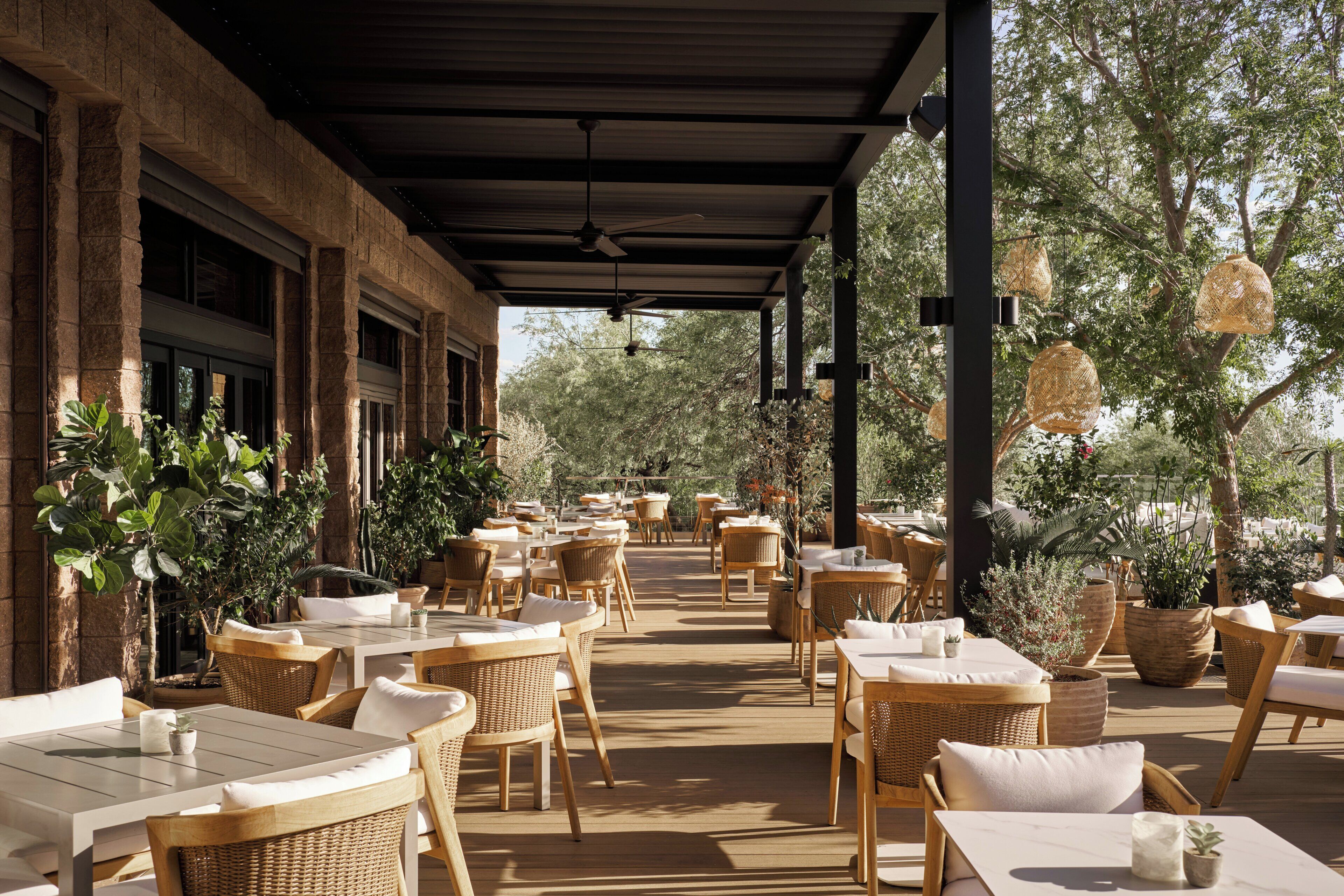 An outdoor patio with wicker furniture, potted plants, and a covered area with a ceiling fan.