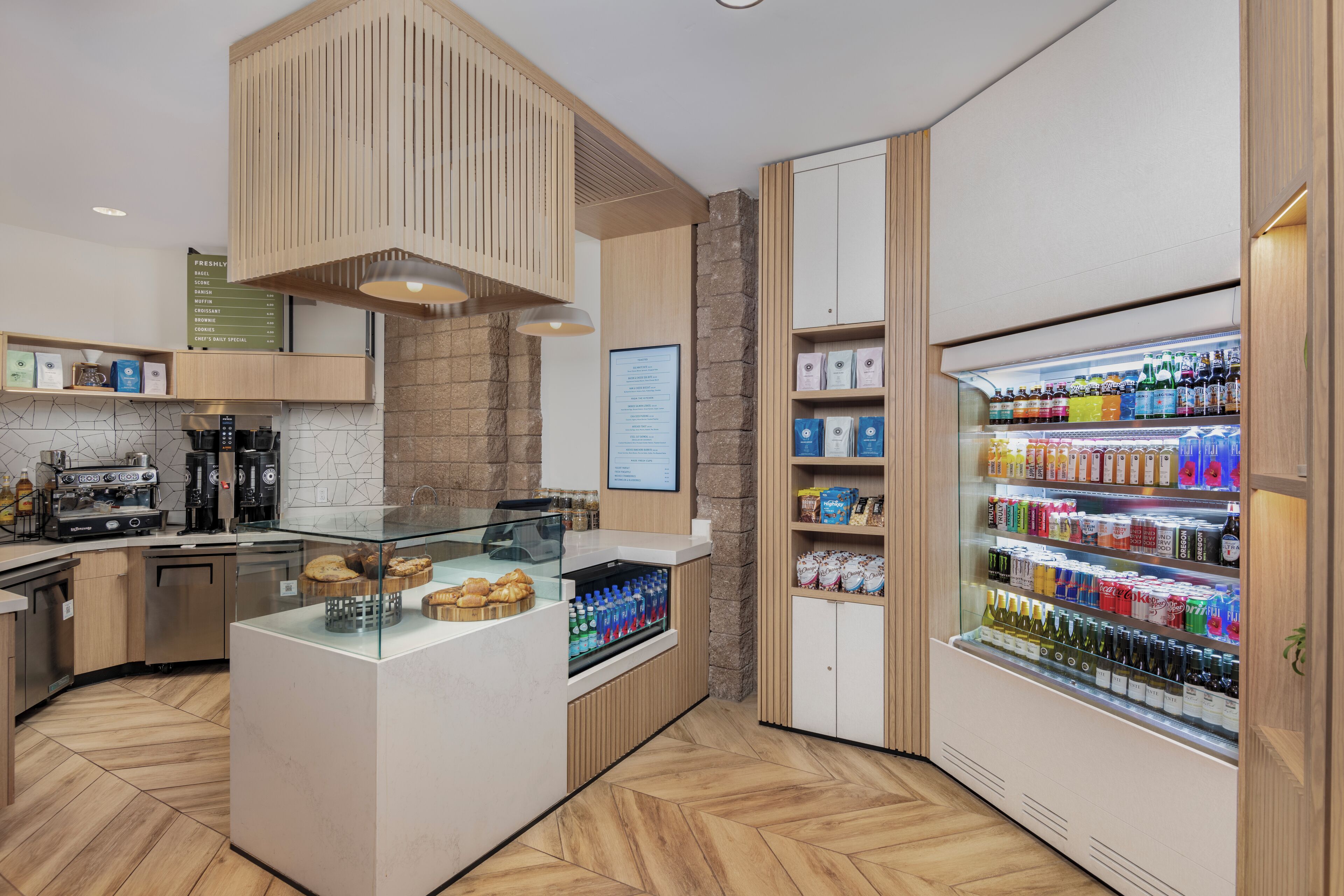 Une cuisine moderne dotée d’un îlot central, d’un espace dédié au café et d’un réfrigérateur pour les boissons.
