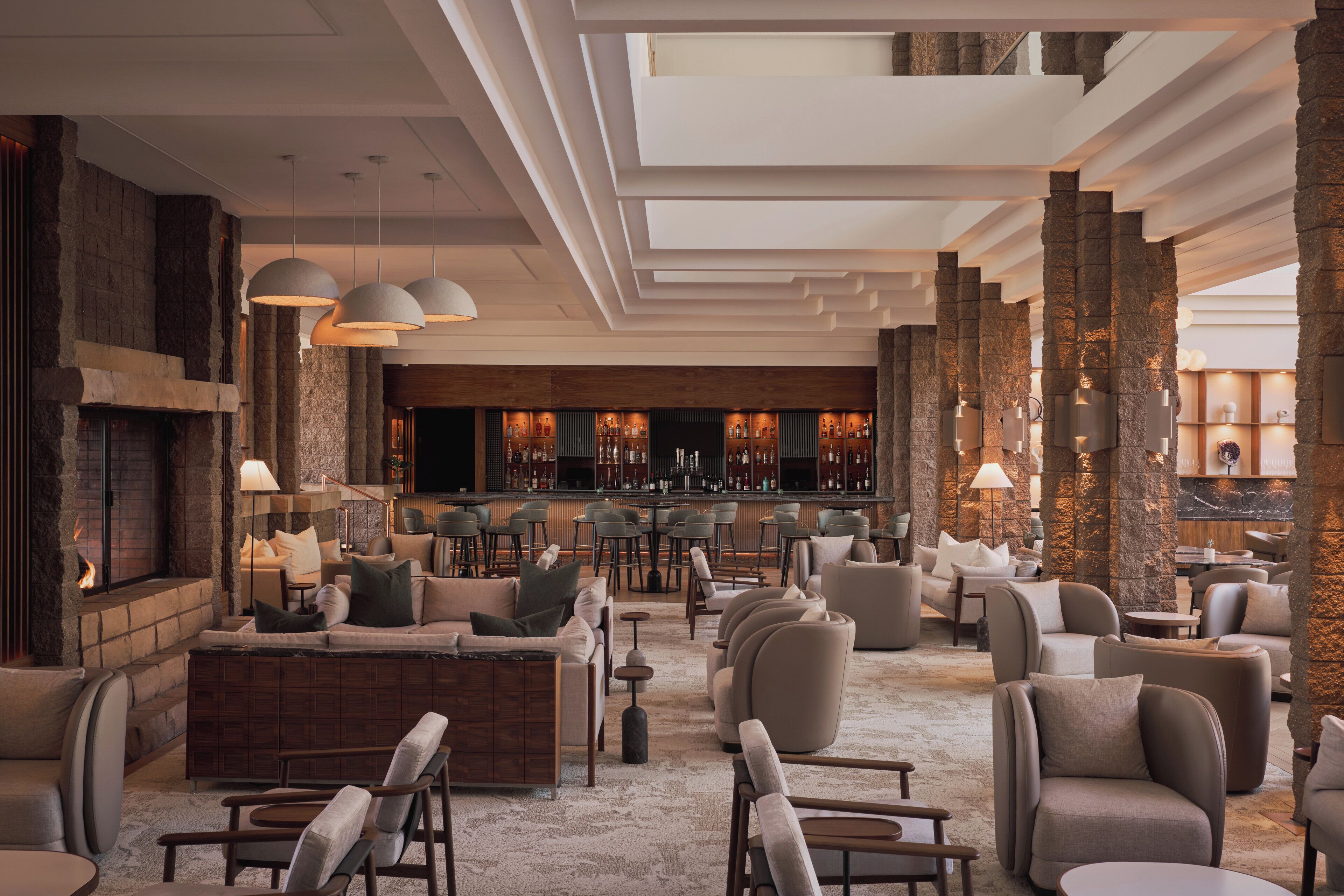 A spacious lounge area with a fireplace, comfortable seating, and a bar in the background.
